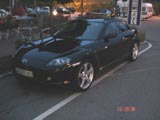 A photo of the front of a Mazda RX8 taken in a German carpark. I love this car. It doesn't have aconventioal engine with up-down piston motion. It's got a rotary engine. 200 hp out of a 2 liter engine. Very light too.