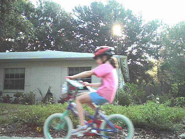 Kathryn speeding by our house on the sidewalk