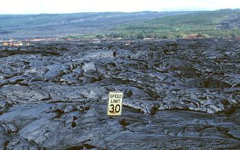 A volcanic lava flow almost buries a street sign in Hawaii.