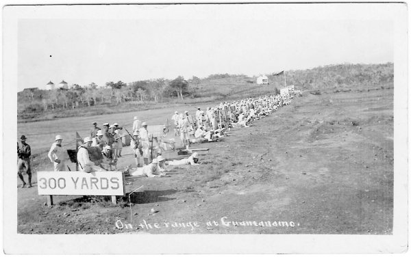 men with guns, sign '300 YARDS', hand caption 'On the range at Guantanamo.'