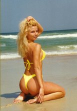 Rear view of Heather kneeling on beach in bikini