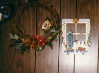 picture of a wreath with a small birdhouse and a mock window witha birdhouse on the wall