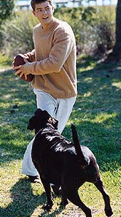 Josh throwing a football with a black dog nearby