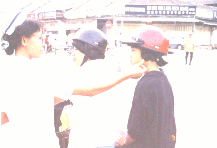 A nurse checking motorcyclist's helmets to see if they are worn properly.