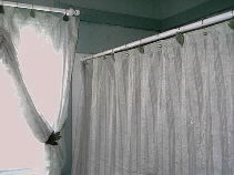 The window and shower curtains have matching holders of rings and designed leaves.