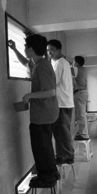 Some youth volunteers from a young mens group happily extend their hands in cleaning the windows and walls.