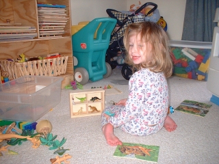 Katie putting plastic dinos in puzzle box