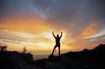 Photo of girl in the sunset stretching her arms to celebrate some accomplishment.