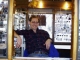 Man sitting in homemade jewelry booth on wheels.   Click to enlarge.