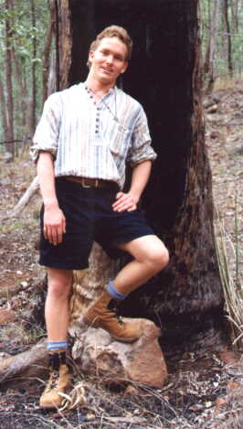 Malcolm leaning onto a tree