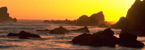 Photo of a sunset by a rocky shoreline