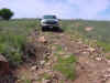 A truck on a dirt road with rocks on the road